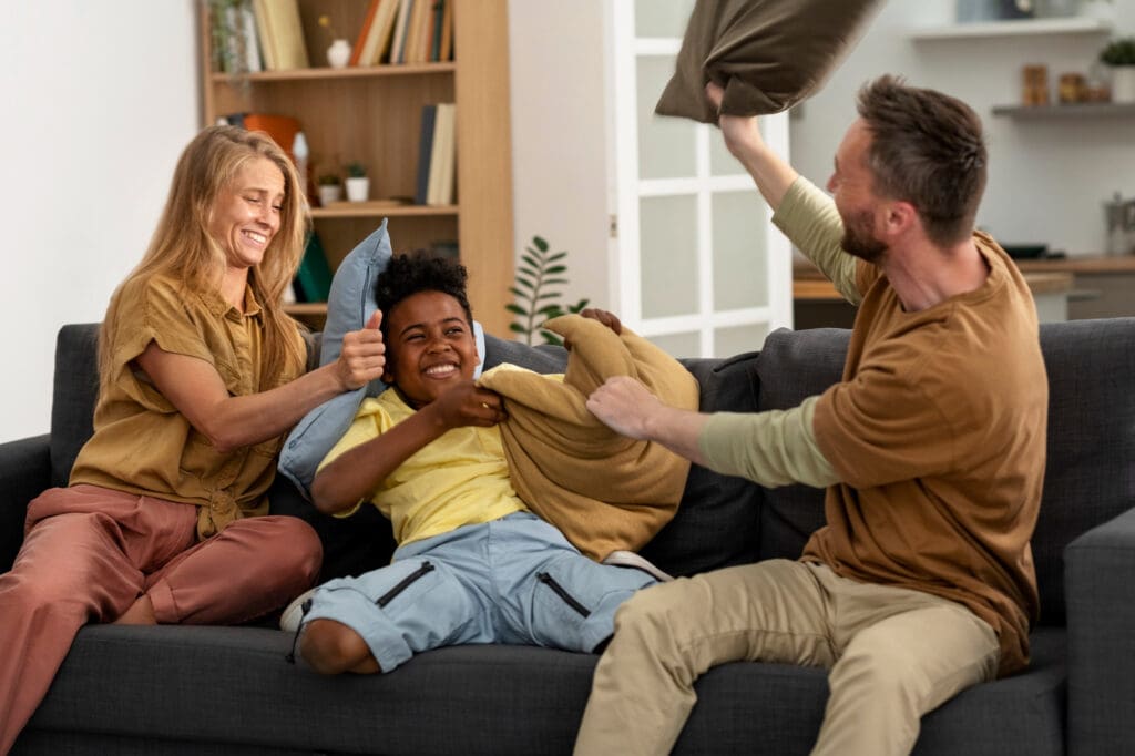A happy family playing together on their living room sofa, sharing joyful moments in their cozy space. Their lease to own home in Raleigh provides comfort and stability, creating the perfect environment to build lasting memories.