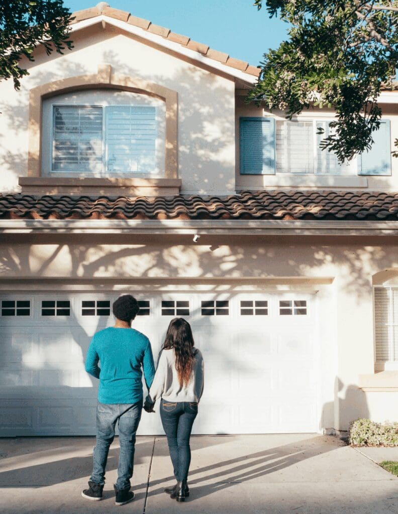 Young couple standing confidently in front of their new home, symbolizing alternative paths to homeownership—such as Lease-to-Own Raleigh—in 2025 without a traditional mortgage.