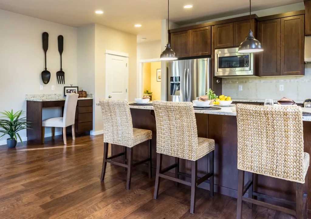 Modern kitchen interior in lease to own Greensboro home--building equity without a mortgage -- with wooden cabinets, stainless steel appliances, and woven bar stools around a granite island.